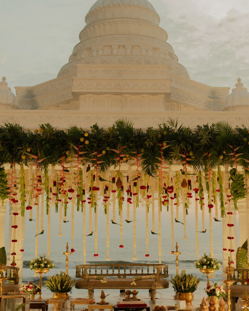 Indian wedding mandap with flower garlands in front of a white temple
