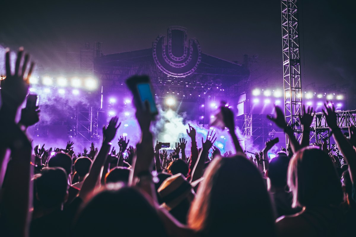 Purple stage lighting and truss above a festival crowd