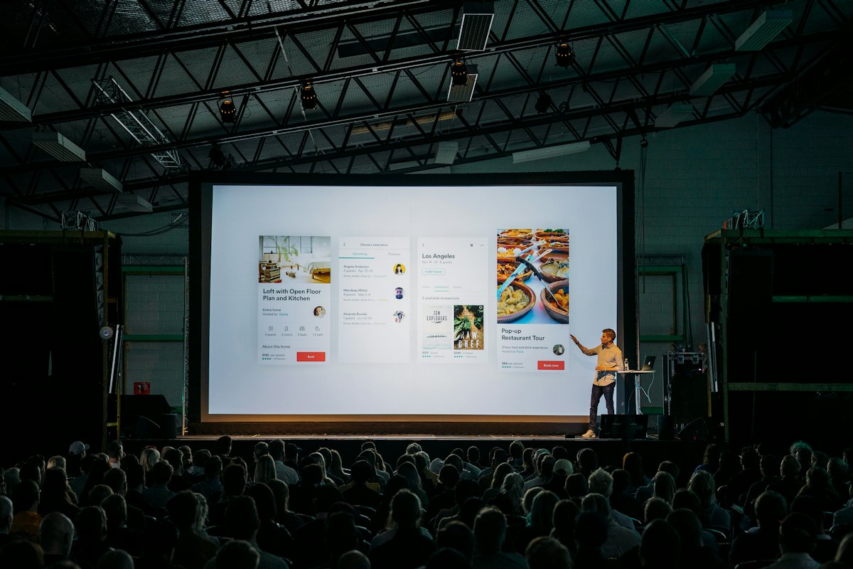 Presenter on stage in front of a large projection screen