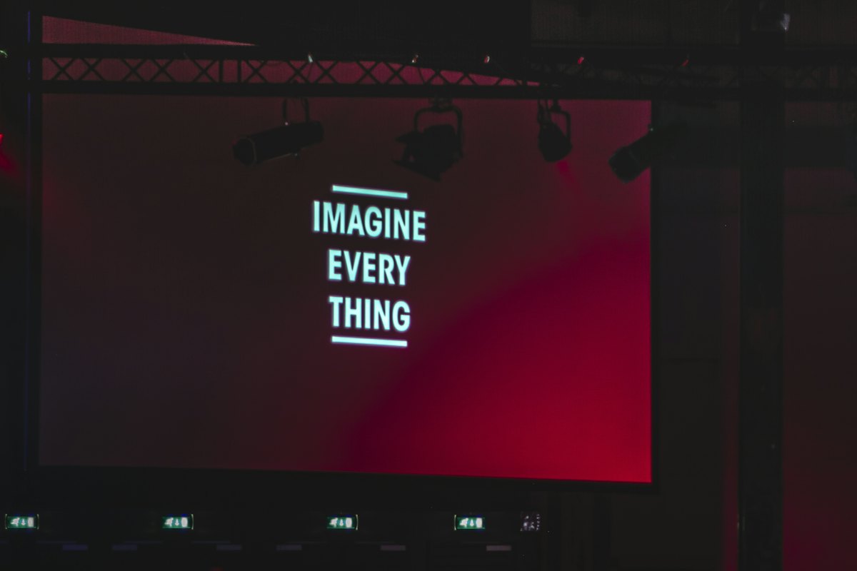 Large screen display above a darkened event hall