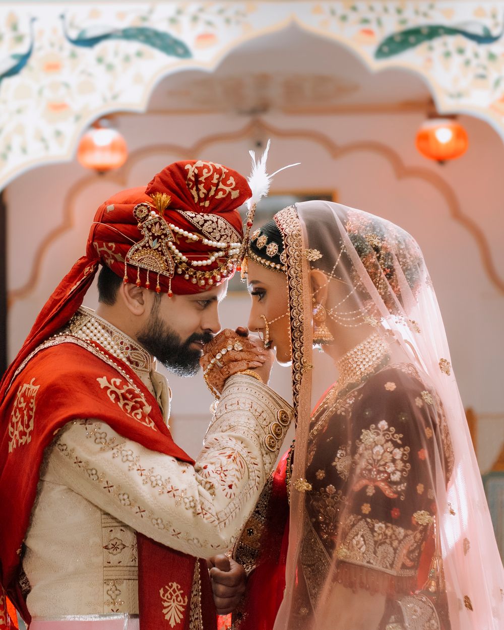 Bride and groom in traditional wedding attire against a painted archway