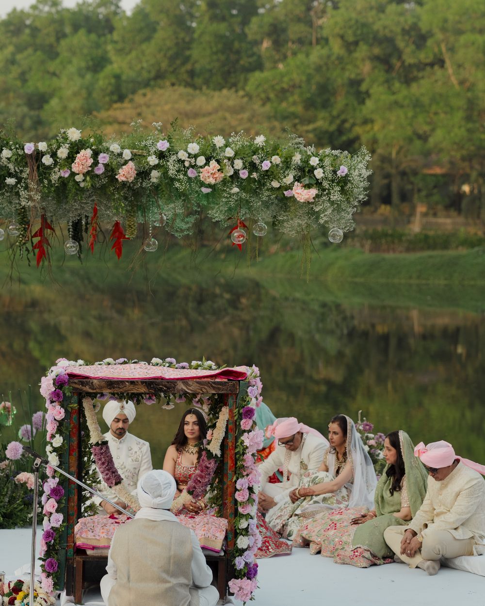 Outdoor wedding ceremony on a floral platform beside a lake