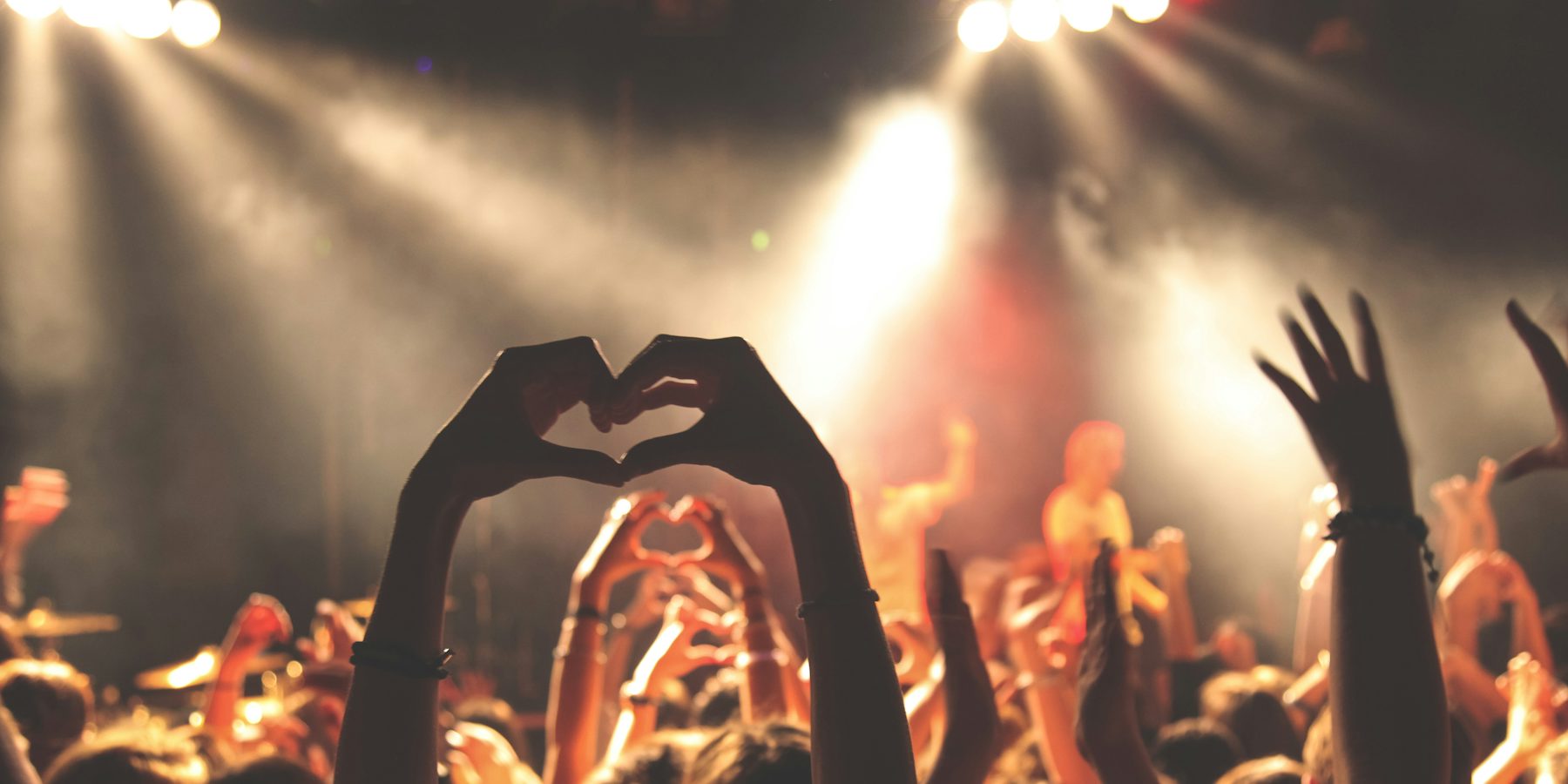 Crowd raising their hands in front of a lit stage