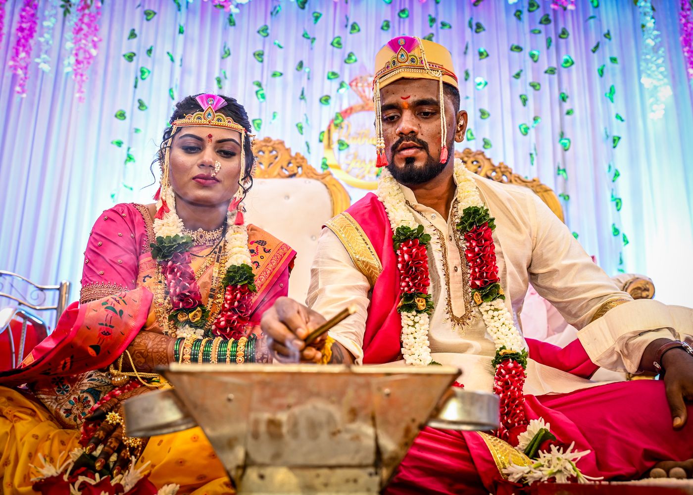 Bride and groom performing wedding rituals in traditional attire