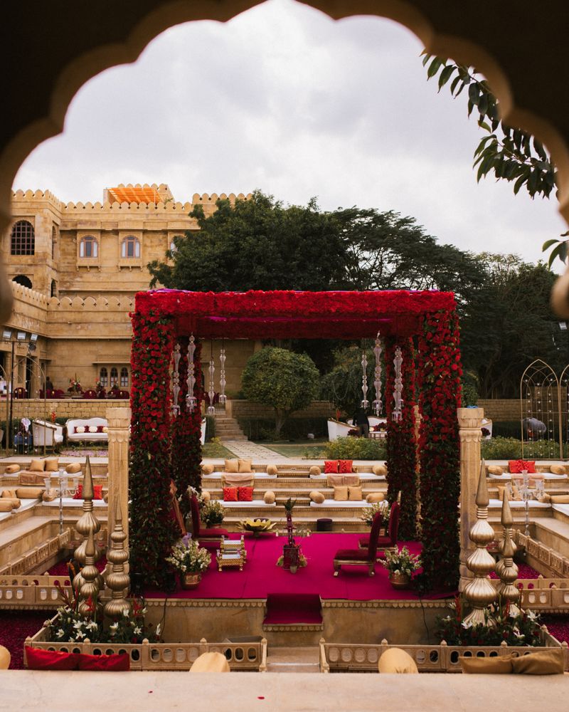 Red and gold wedding mandap in a royal fort courtyard